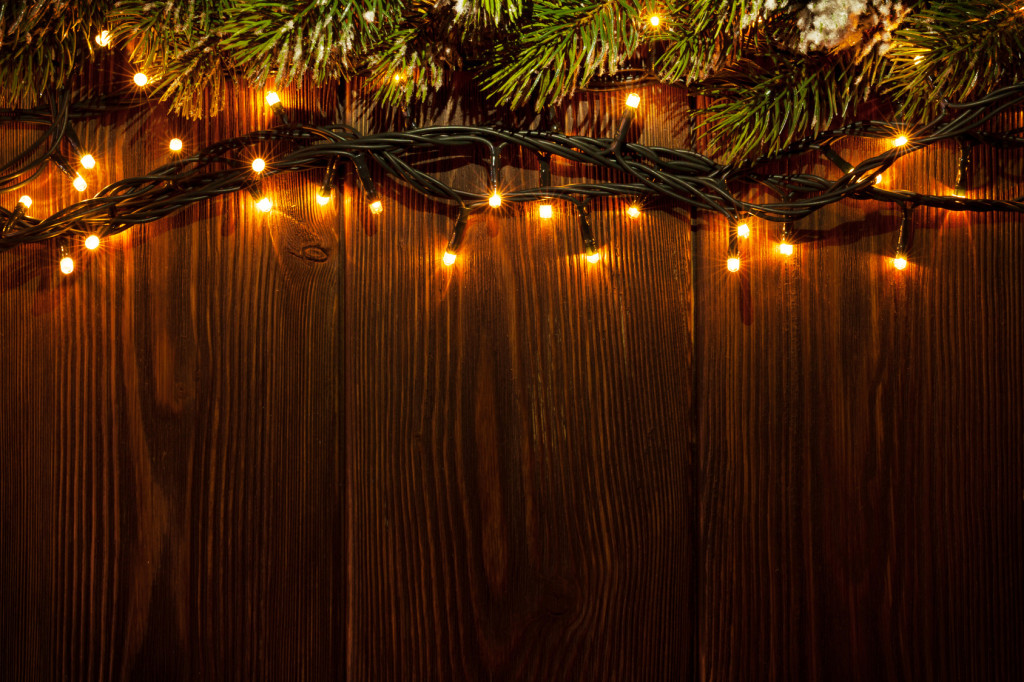 Christmas tree branch and lights on wooden background. View with copy space